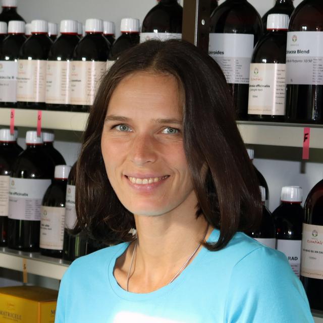 Porträt einer lächelnden Frau vor einem Regal mit verschiedenen Kosmetik- und Wellnessprodukten