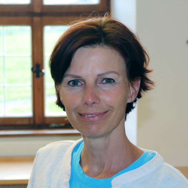 Porträt einer lächelnden Frau mit dunklen Haaren vor einem Fenster